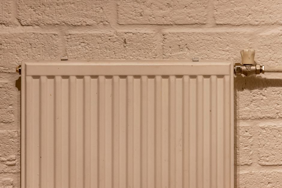 A slim white panel space heater mounted on a wall