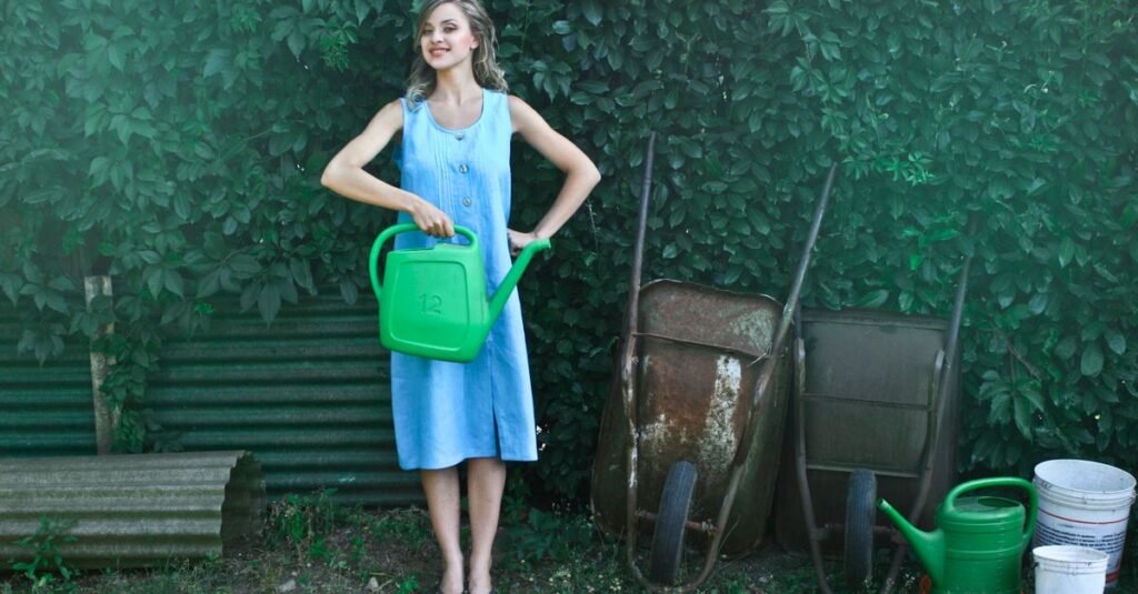 Woman with watering cans beside a garden shed