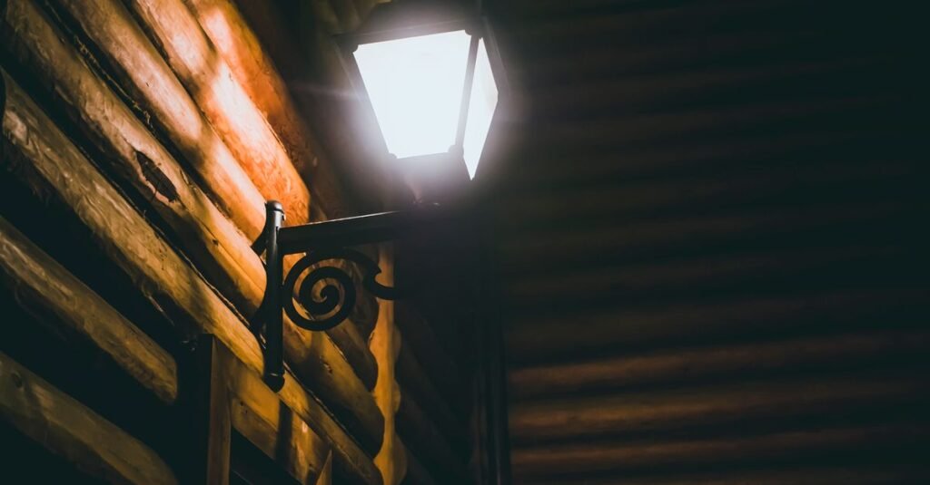 Wall lantern casting light across dark siding
