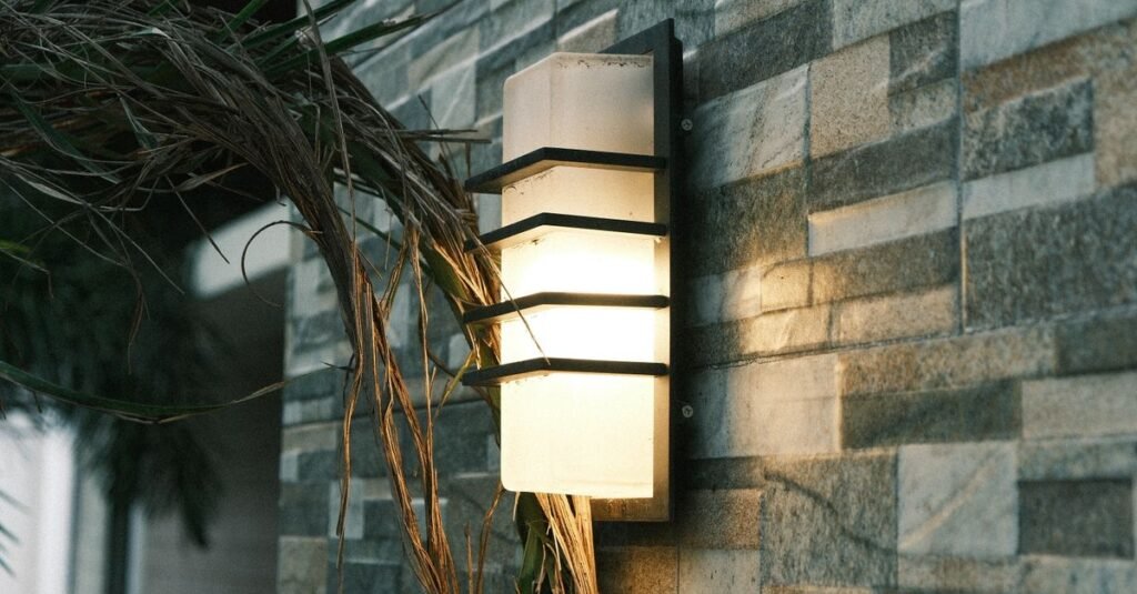 Modern wall sconce glowing on a stone facade