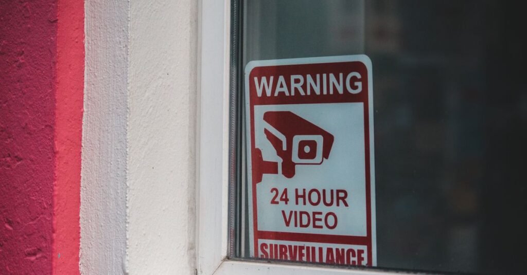 24-hour video surveillance warning sign in a window